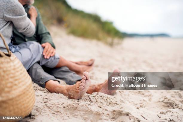 close up of senior couple feet sitting on sandy beach - older couple hugging on beach stock pictures, royalty-free photos & images