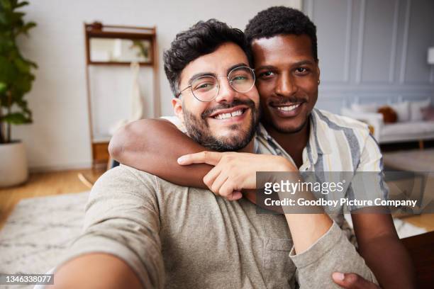 affectionate young gay couple smiling while taking selfies at home - gay couple in love stock pictures, royalty-free photos & images