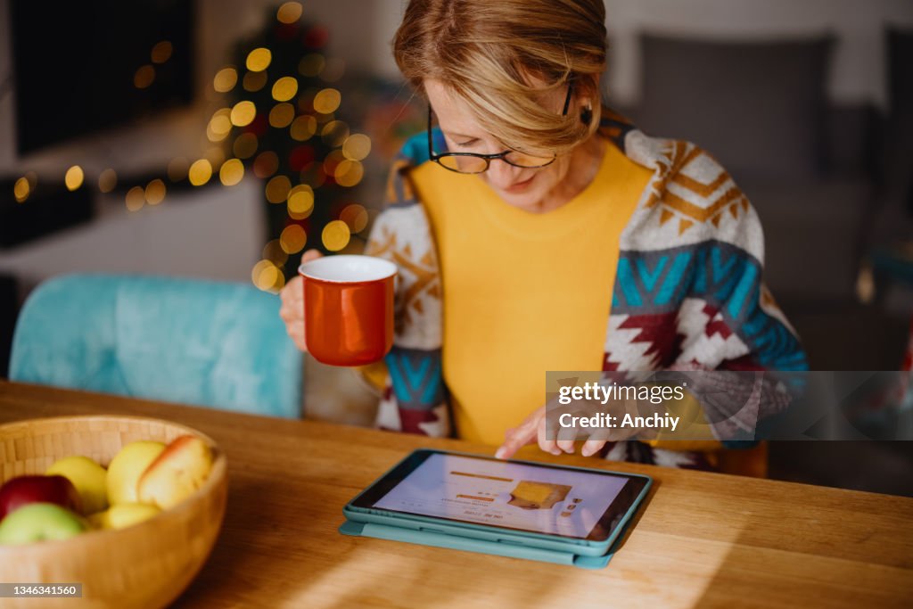Mature woman using digital tablet for online Christmas shopping