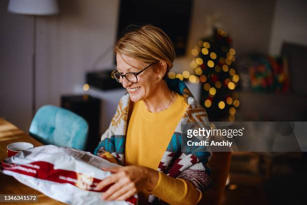 smiling woman unpacking parcel sitting at home - debit cards credit cards accepted stock pictures, royalty-free photos & images