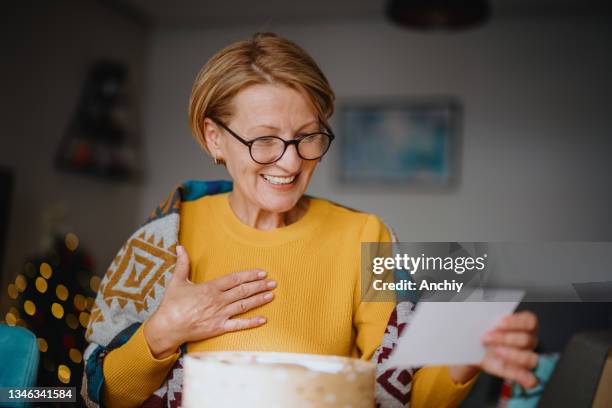 smiling woman unpacking parcel sitting at home - responder imagens e fotografias de stock