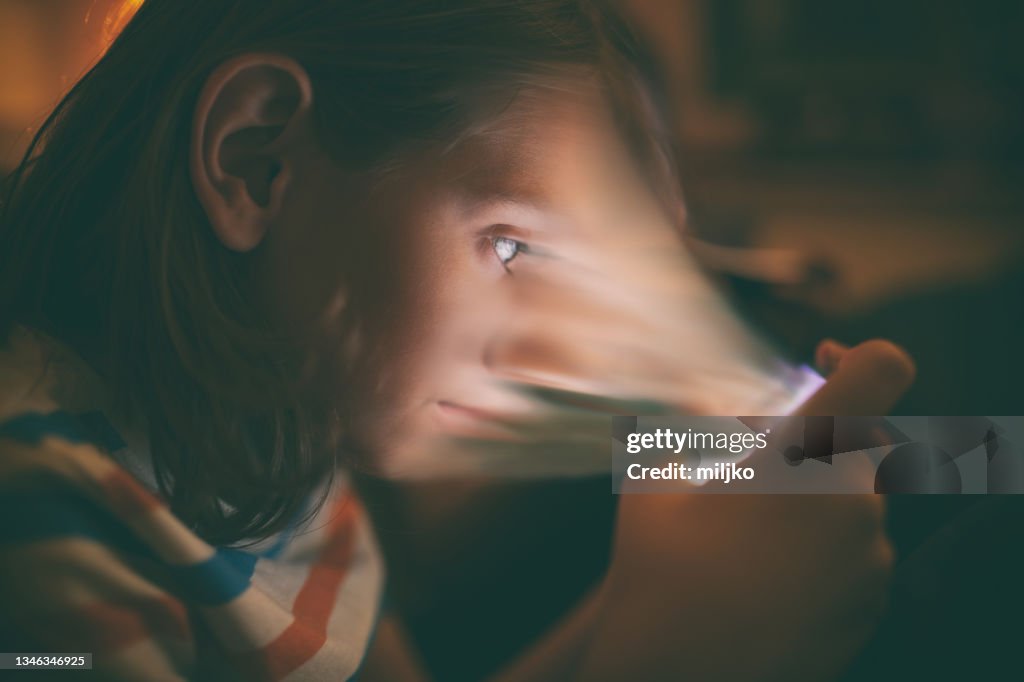 Menino jogando no celular em sua cama