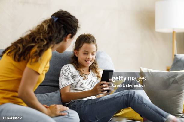 happy girl using cell phone and ignoring her mother at home. - stupid girls stock pictures, royalty-free photos & images