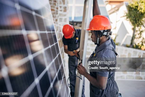 male workers installing solar panels - energy efficient building stock pictures, royalty-free photos & images