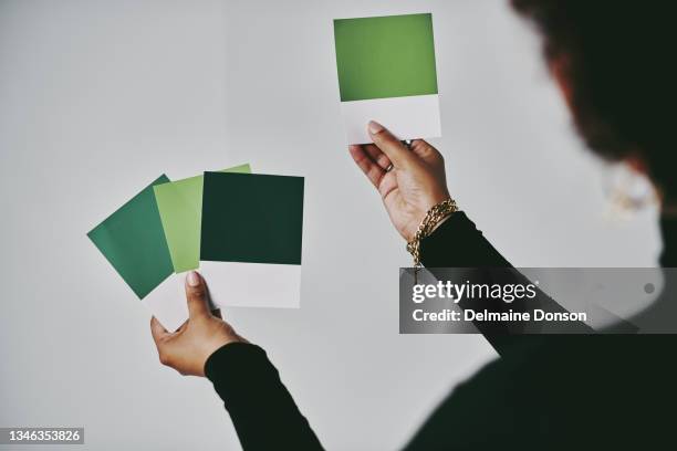 cropped shot of an unrecognizable artist standing alone and holding up colour swatches in her studio - colour swatch stockfoto's en -beelden