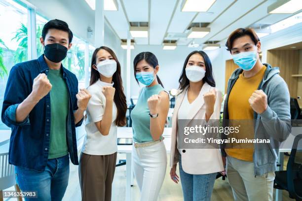 group of asian team business people team wearing face mask standing together ready for success in office during coronavirus epidemic. - thailand covid stock pictures, royalty-free photos & images