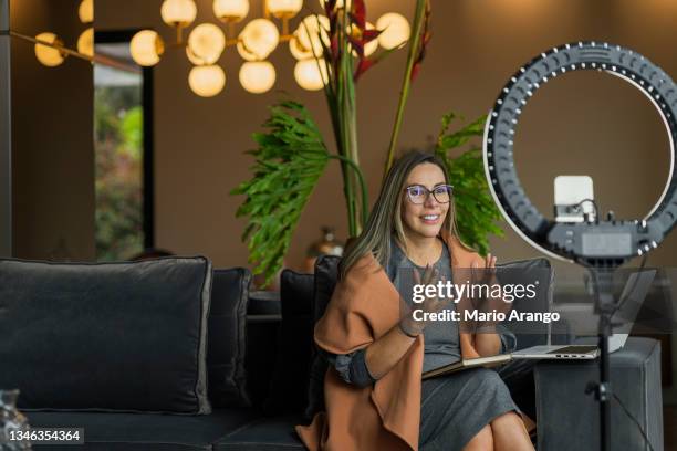 mulher bonita realizando uma live de casa enquanto usa seu anel de luz para iluminar a si mesma e seu celular para fazer o vídeo - filmar - fotografias e filmes do acervo