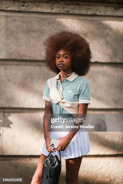 Fashion Week Guest wearing a blue shirt, a beige pullover and a white skirt outside Lacoste Show on October 05, 2021 in Paris, France.