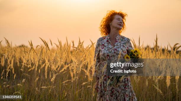 senior red haired woman breathes fresh air - orange dress stock pictures, royalty-free photos & images