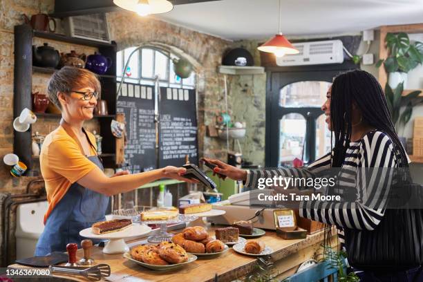 woman paying for goods with her mobile phone. - danish pastry stock pictures, royalty-free photos & images