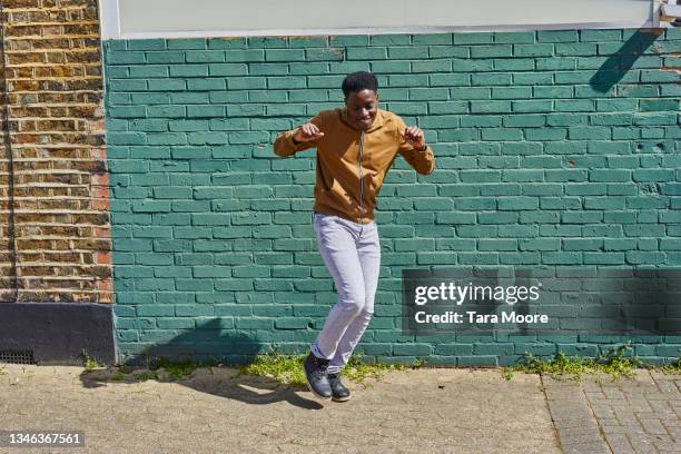man dancing in front of brick wall. - ダンス ストックフォトと画像