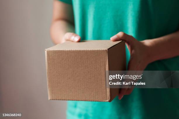 a young southeast asian woman is holding a carton box package delivery indoor - daily life in manila stock pictures, royalty-free photos & images