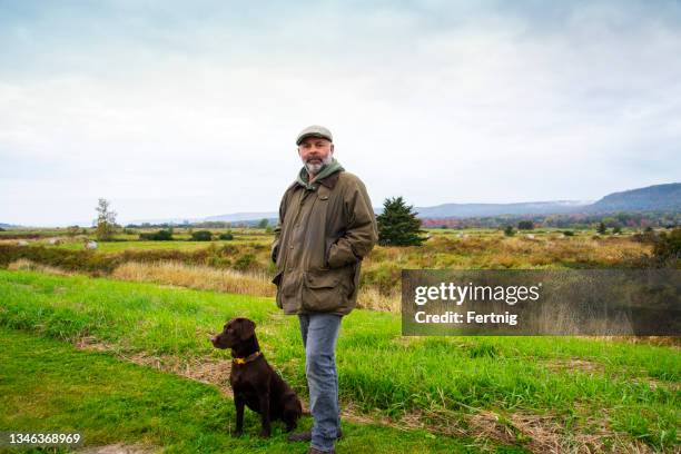 a mature man in the countryside on a autumn day with his dog - middle age man and walking the dog stockfoto's en -beelden