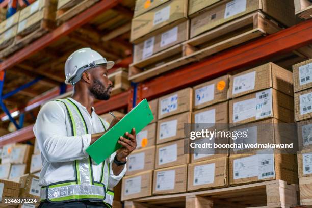 warehouse worker in uniform is inspecting shipment for delivering to customers. - birth certificate foto e immagini stock