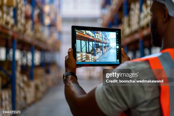 smart warehouse management system.worker hands holding tablet on blurred warehouse as background - digital store stock-fotos und bilder