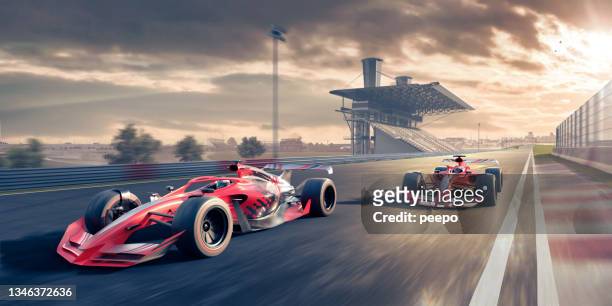 dos coches de carreras rojos que se mueven a gran velocidad a lo largo de la pista de carreras al atardecer - gran premio de carreras de motor fotografías e imágenes de stock