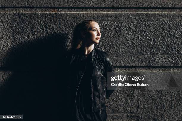 young women standing against dark wall. - long shadow shadow stock pictures, royalty-free photos & images