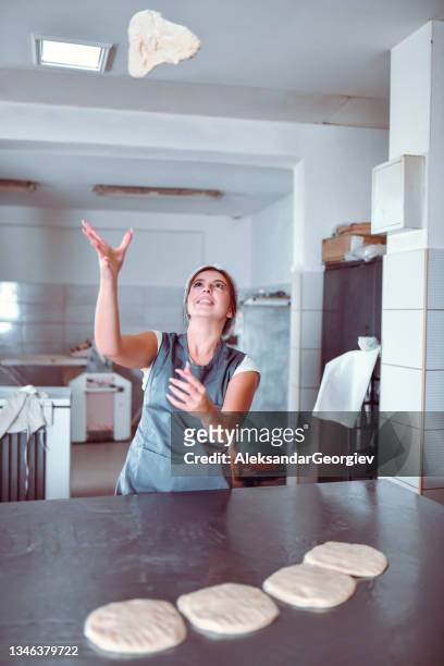 femmina che lancia l'impasto della pizza in aria mentre lo impasta prima della cottura - pizza toss foto e immagini stock