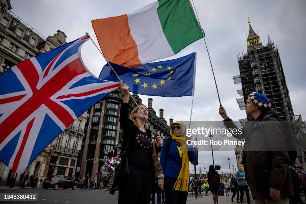 Anti-Brexit protesters wave the flags of the United Kingdom, Ireland and European Union outside Parliament on October 13, 2021 in London, England.