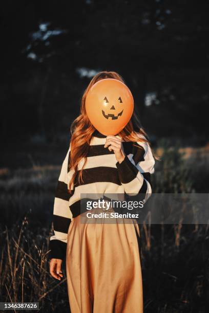 a woman is behind a halloween balloon - halloween party - fotografias e filmes do acervo