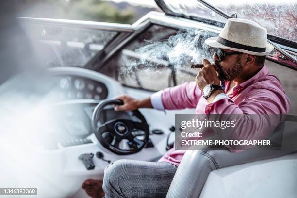 attractive businessman with a cigar on his yacht - extreme wealth stock pictures, royalty-free photos & images