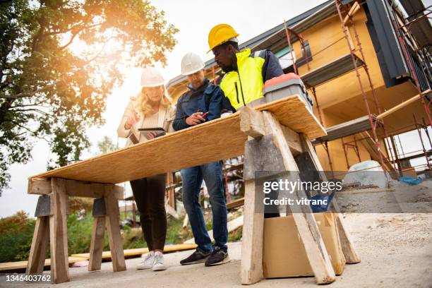 construction project team working on a blueprint at construction site - foundations gender equality discussion stock pictures, royalty-free photos & images