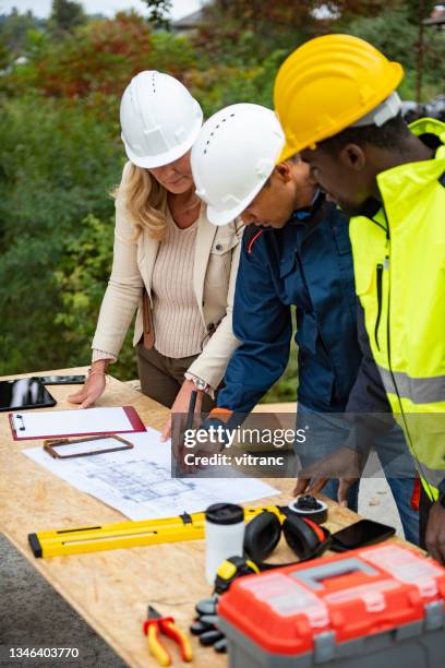 construction project team working on a blueprint at construction site - structural engineer stock pictures, royalty-free photos & images