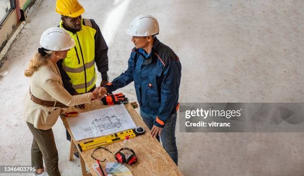 group of architects correcting a construction plan at construction site - handshake site stock pictures, royalty-free photos & images