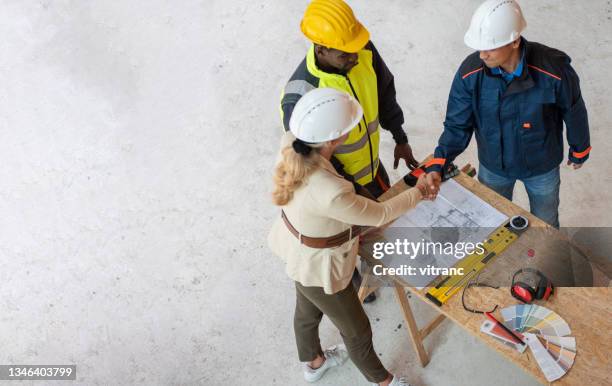 group of architects correcting a construction plan at construction site - blueprint stock pictures, royalty-free photos & images