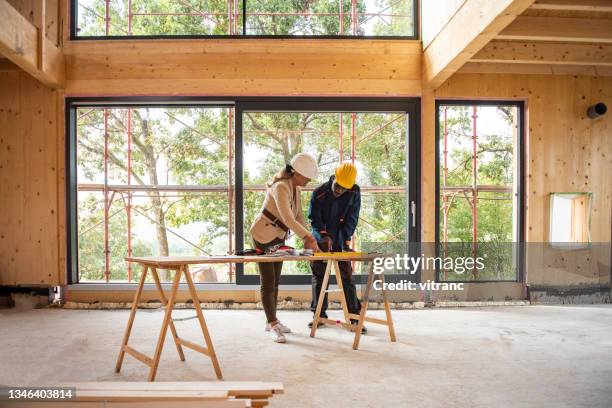 architektin und bauarbeiterin schaut sich pläne an - bauunternehmer stock-fotos und bilder