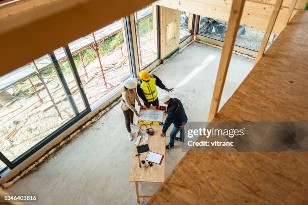 groupe d’architectes corrigeant un plan de construction sur un chantier - wood stock photos et images de collection