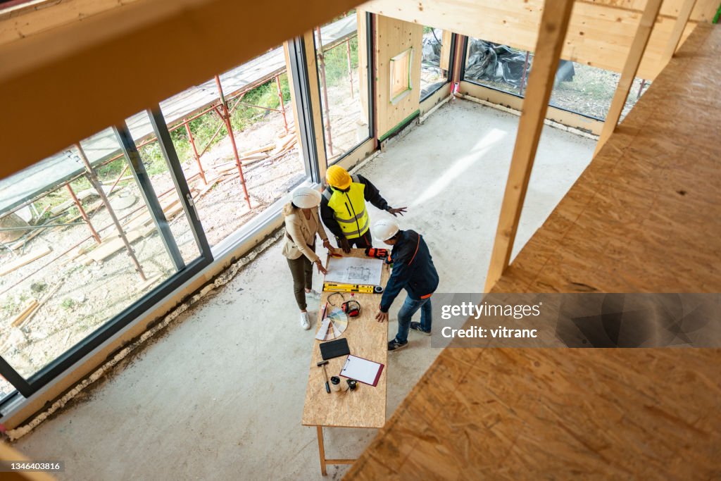Gruppo di architetti che correggono un piano di costruzione in cantiere