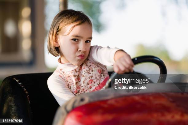 kleines mädchen, das autoscooter fährt, auf dem spielplatz im freien spielt - girl driving stock-fotos und bilder