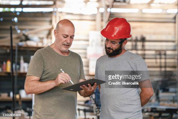 middle aged architect describing his project to the carpenter in the carpentry workshop - the project portraits stock pictures, royalty-free photos & images