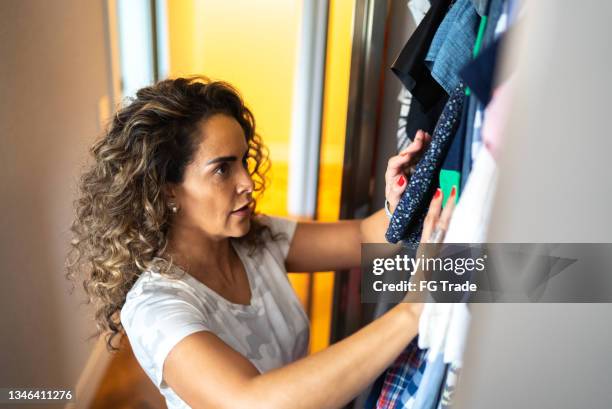 reife frau, die kleidung im schrank zu hause wählt - morgens anziehen stock-fotos und bilder