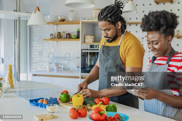 young couple cooking together in the kitchen - reading cookbook stock pictures, royalty-free photos & images