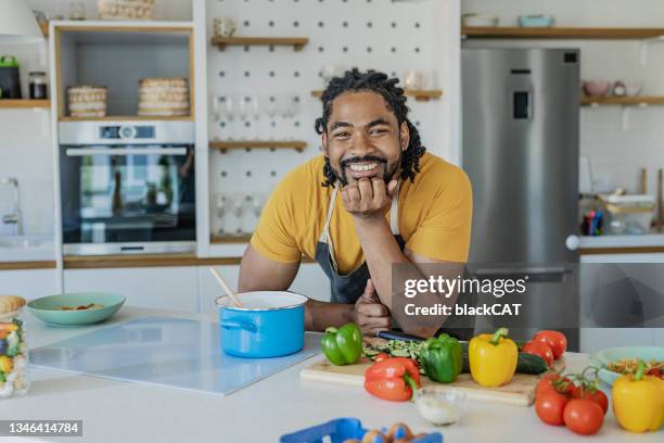 portrait d’un jeune homme préparant un repas en cuisine - homme cuisine photos et images de collection