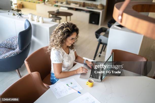 mature woman using laptop working at home - financial planner stockfoto's en -beelden