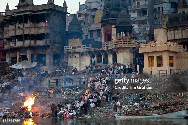 Body bathed in River Ganges and traditional Hindu cremation on funeral pyre at Manikarnika Ghat in Holy City of Varanasi, Benares, India