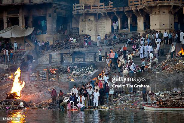 Body bathed in River Ganges and traditional Hindu cremation on funeral pyre at Manikarnika Ghat in Holy City of Varanasi, Benares, India