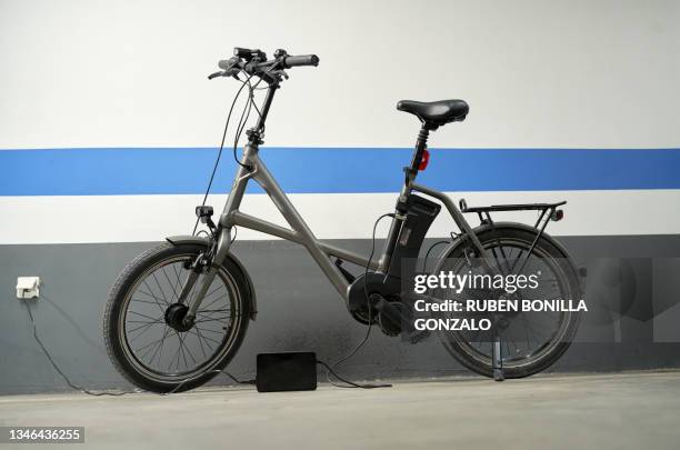 electric bicycle charging the electrical battery at garage. environmental concept. - e bike stock pictures, royalty-free photos & images
