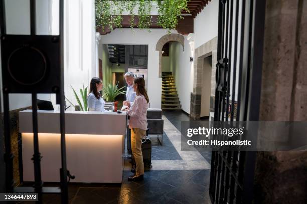 feliz pareja de viajeros haciendo el check-in en la recepción del hotel - huésped fotografías e imágenes de stock