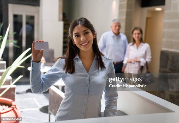 feliz recepcionista del hotel sosteniendo una llave de tarjeta para sus clientes - tarjeta de lealtad fotografías e imágenes de stock
