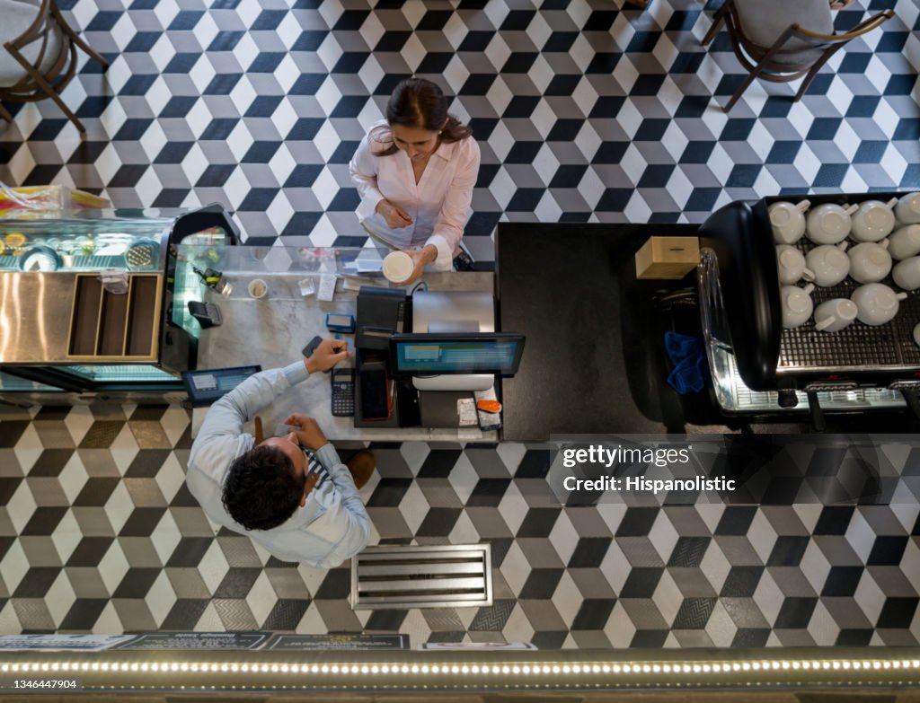 Woman at a cafe buying a cup of coffee to go