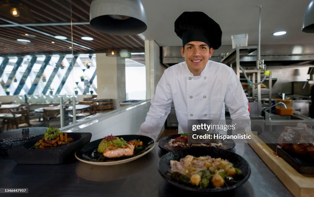 Happy chef presenting his plates in the kitchen of a restaurant