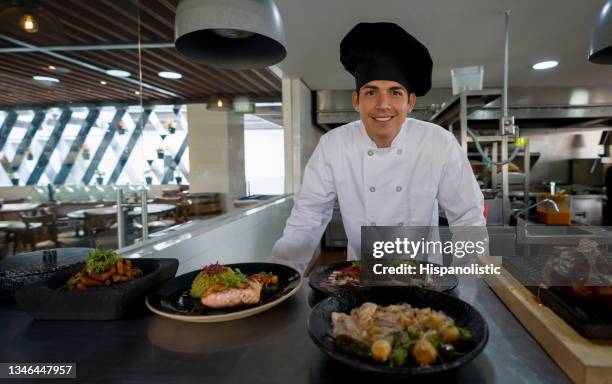 happy chef presenting his plates in the kitchen of a restaurant - diner plates stock pictures, royalty-free photos & images