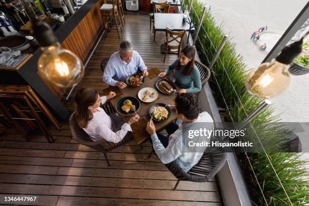 happy family eating together at a restaurant - family four people stock pictures, royalty-free photos & images