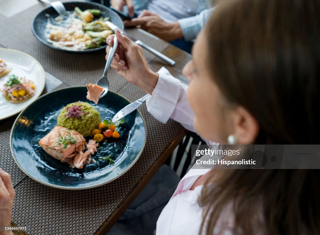 Happy woman eating dinner with her family at a restaurant