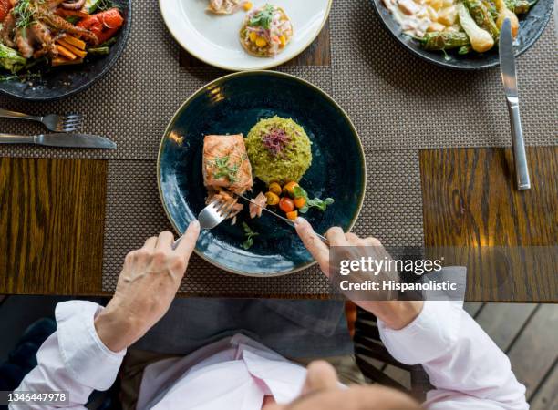 primo piano su una donna che mangia salmone per cena in un ristorante - bar overhead foto e immagini stock
