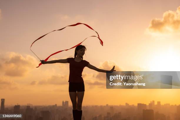 young happy woman dancing with ribbons in the beautiful sunset,morden city background - ribbon dance stock-fotos und bilder